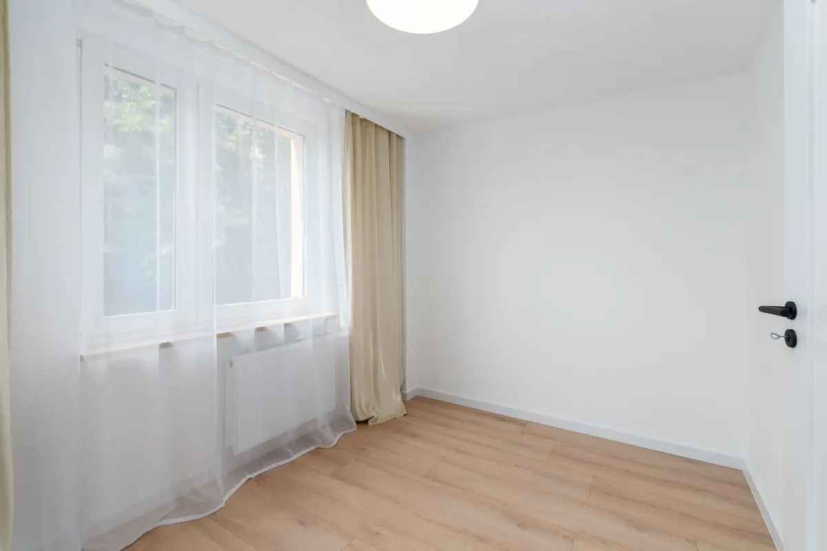 Lichte kamer met gladde witte muren en een raam met vitrage